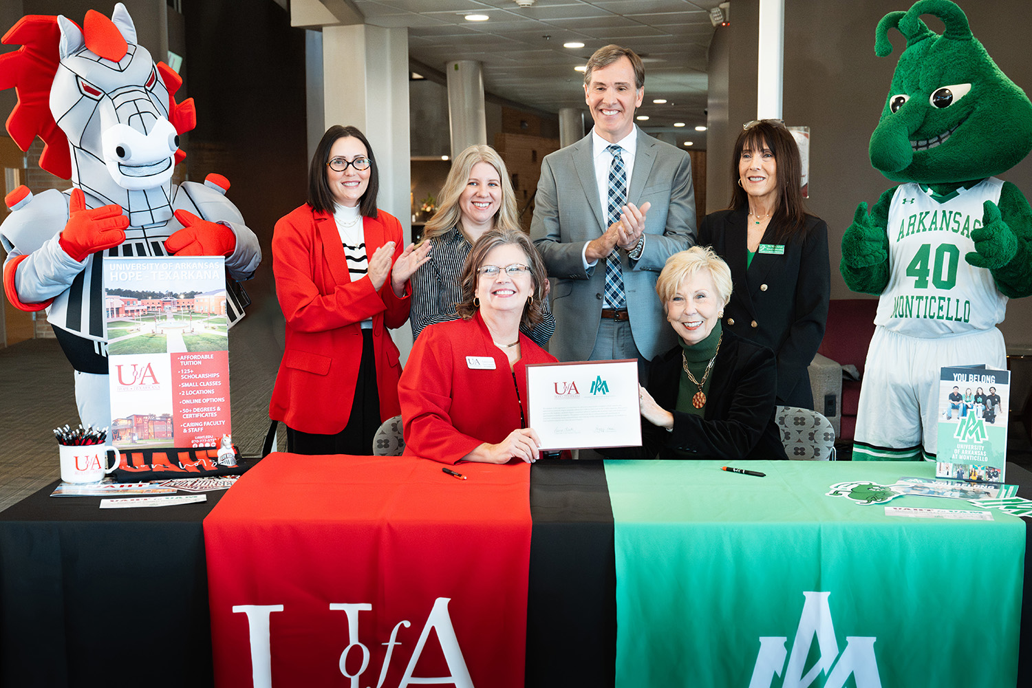 Front row left to right: Laura Clark, UAHT interim chancellor and Dr. Peggy Doss, UAM Chancellor.  Back row: Spike the Iron Horse; Dr. Mikki Curtis, UAHT dean of arts, humanities, and education; Jennifer Teresa, UAHT dean of business and technical education; Chris Thomason, UA System VP for strategic and community college partnerships; Dr. Kim Level, UAM dean of education; and Weezie the Weevil